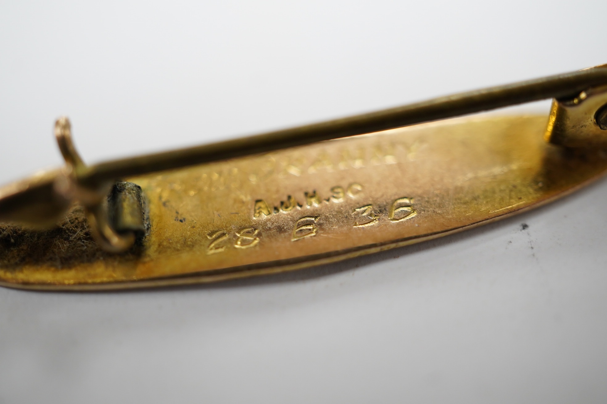 A '9ct and silver' hunting horn bar brooch, 62mm, together with a 1930's yellow metal brooch, with engraved inscription. Condition - fair